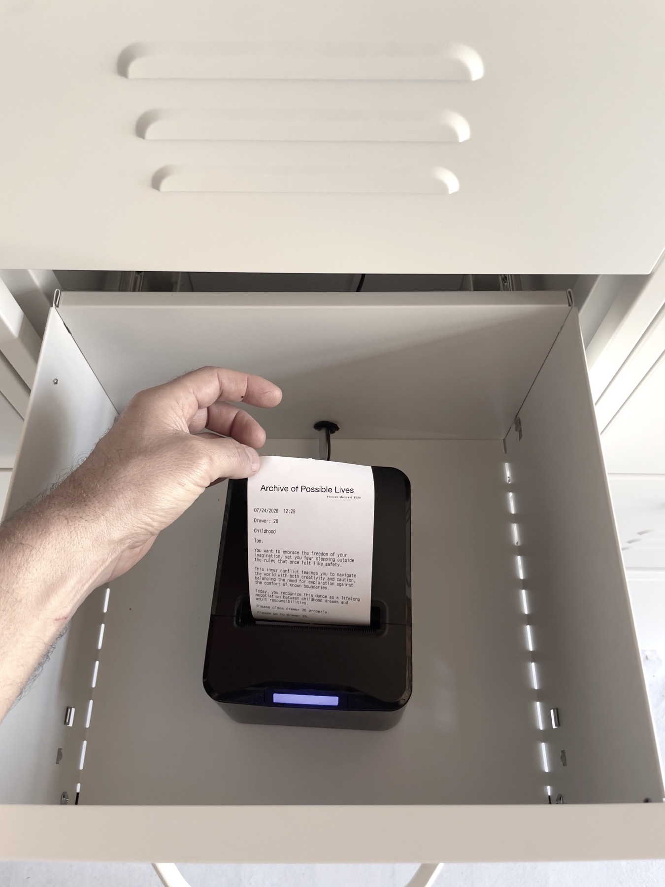 A hand takes a printed biographical fragment from an open drawer