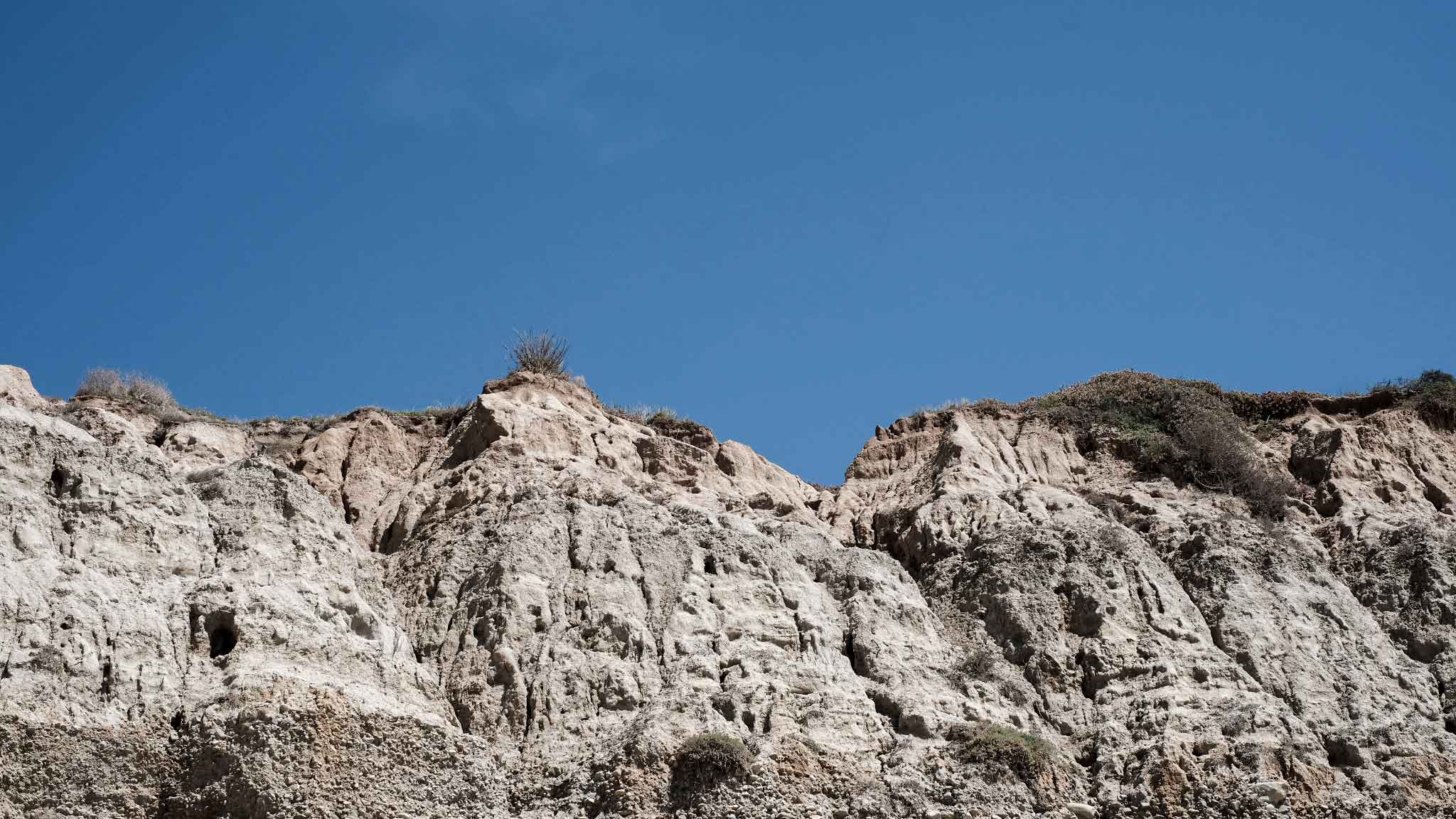Eroded coastal landscape beneath a blue sky